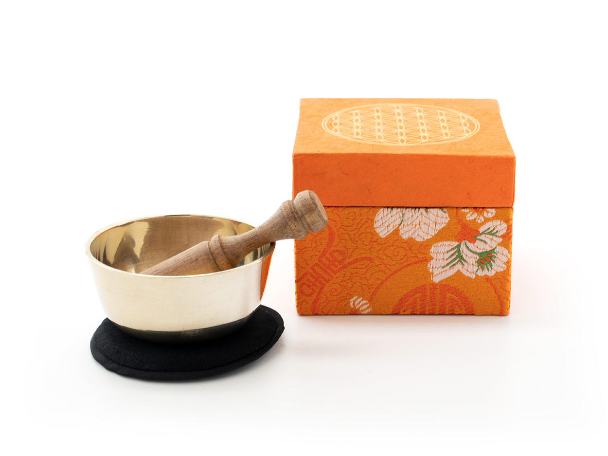 Kleine gegossene Klangschale mit einem hellen Klang und gravierter 'Blume des Lebens'. Verpackt ist die Schale in einer orangefarbenen Geschenk-Box aus handgeschöpftem Naturpapier mit 'Blume des Lebens' Aufdruck. Inklusive Klöppel und Stoffpad.